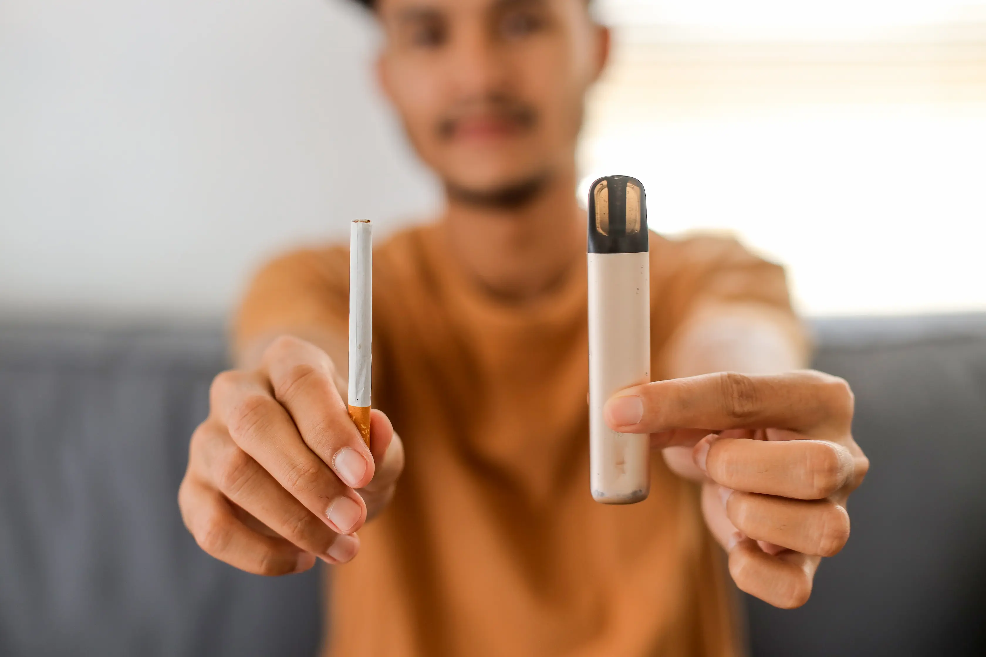 Man holding a cigarette in one hand and a disposable vape in the other, representing the choice to quit