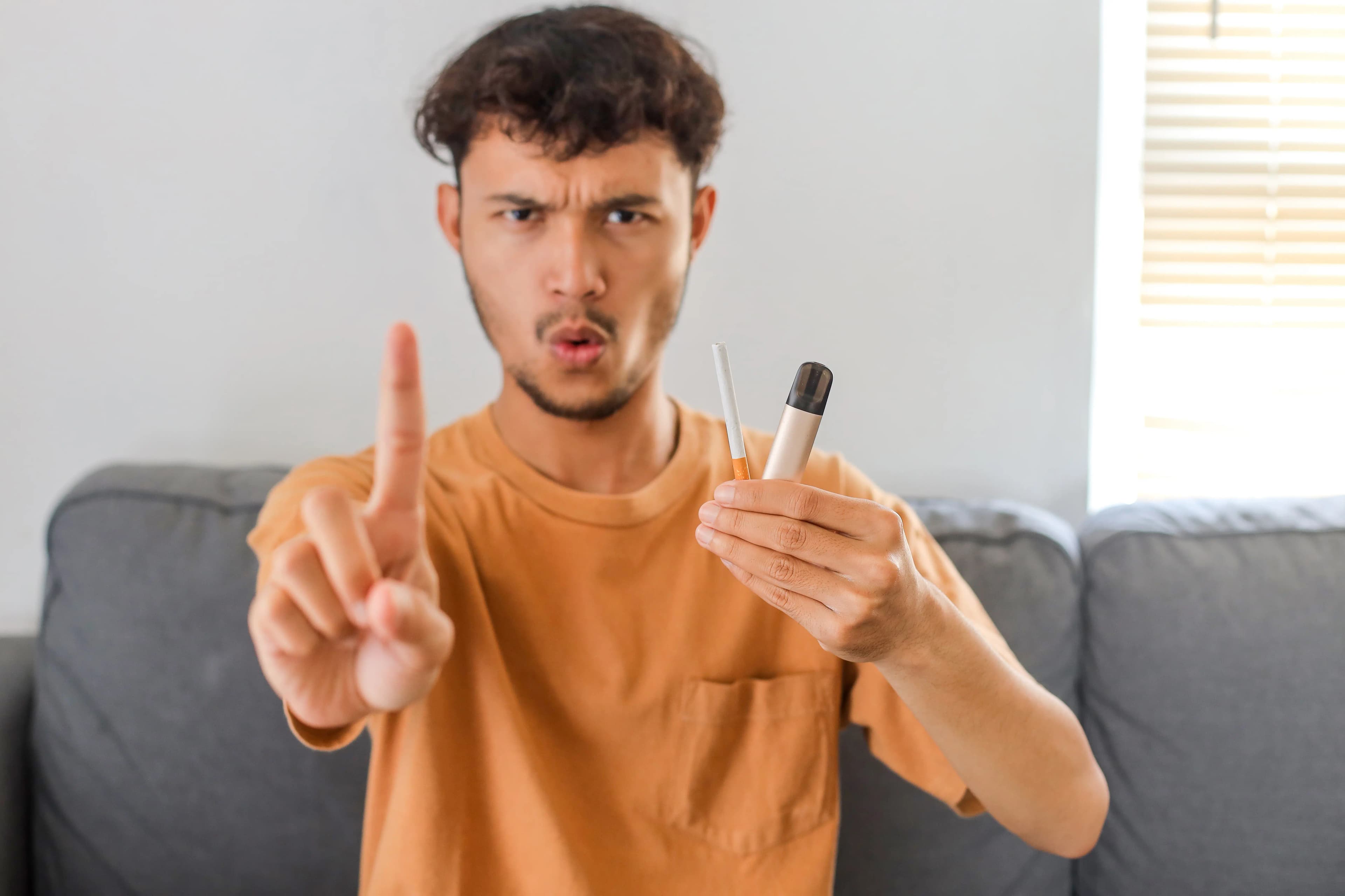 Person holding a cigarette and vape while saying no