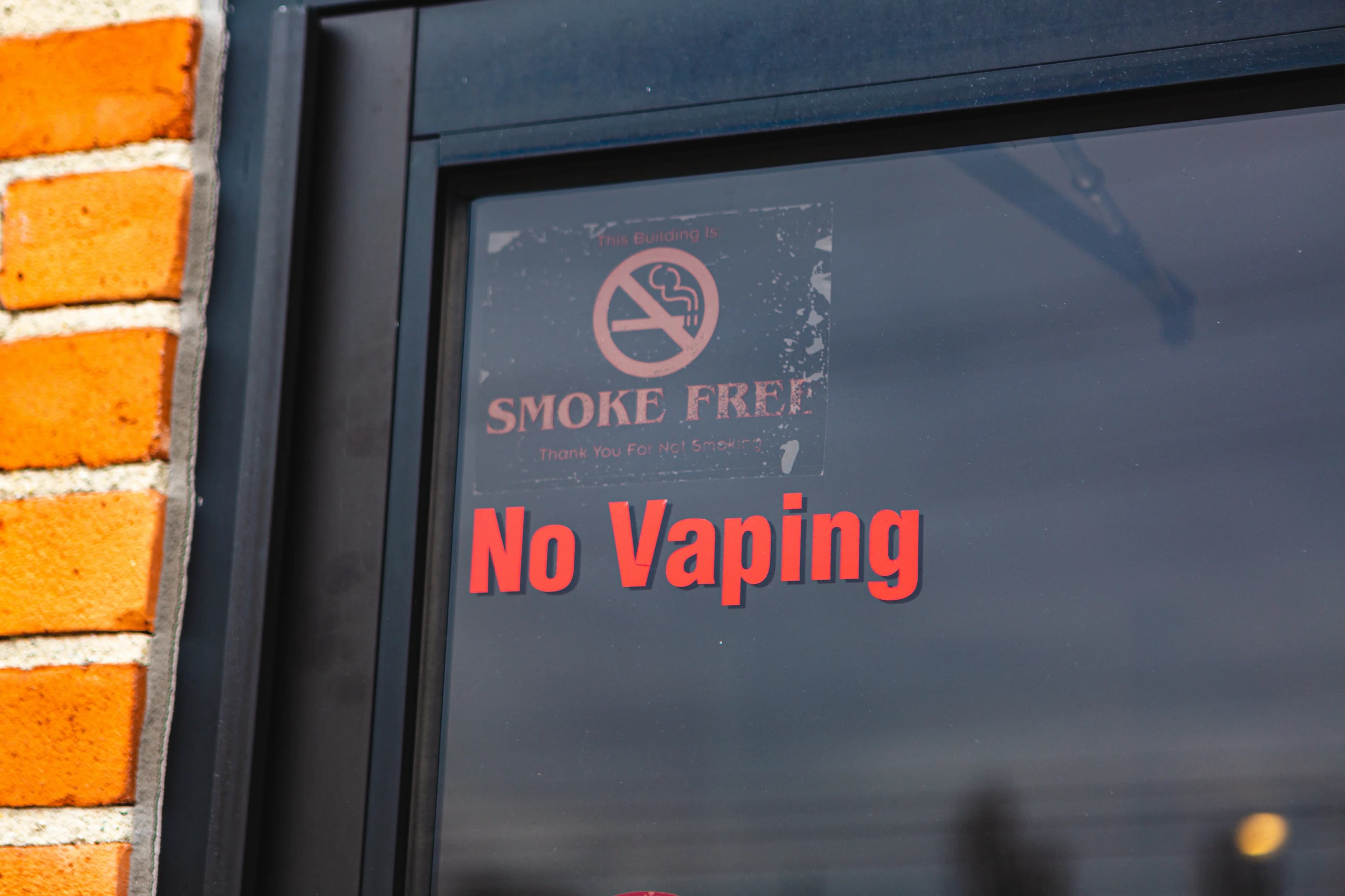 No Vaping sign on a dark glass door
